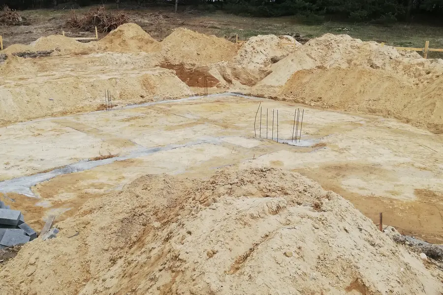 Wyrównany plac budowy z wybranymi ławami fundamentowymi i wypuszczonym zbrojeniem